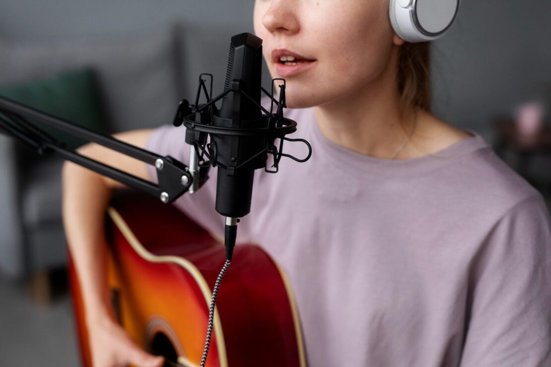 a woman playing acoustic guitar and singing into the microphone