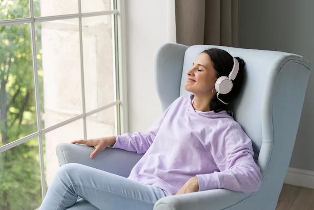 Relaxed woman wearing a headset, sitting on a sofa with her eyes closed