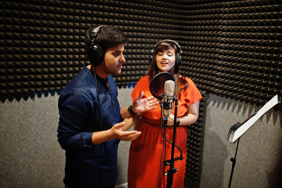 Two individuals singing in a recording studio