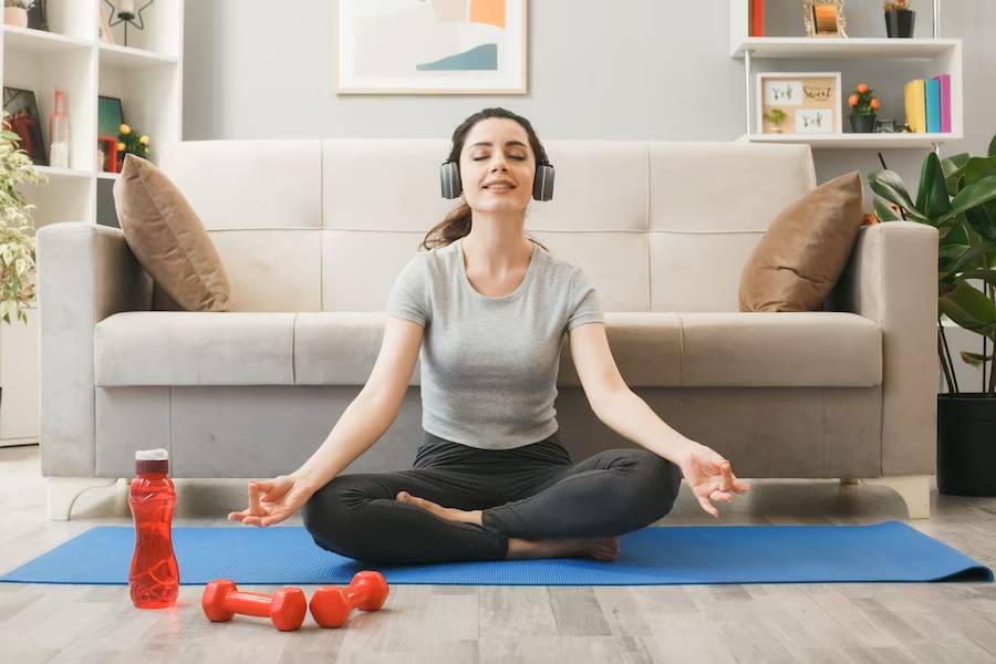 Woman doing breathing exercises with closed eyes and wearing a headset