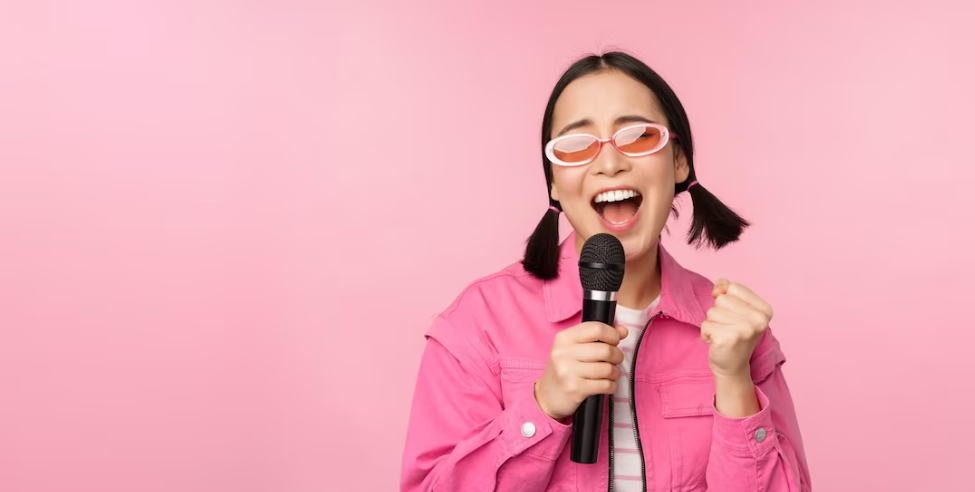 woman in pink and glasses holds a microphone and sings