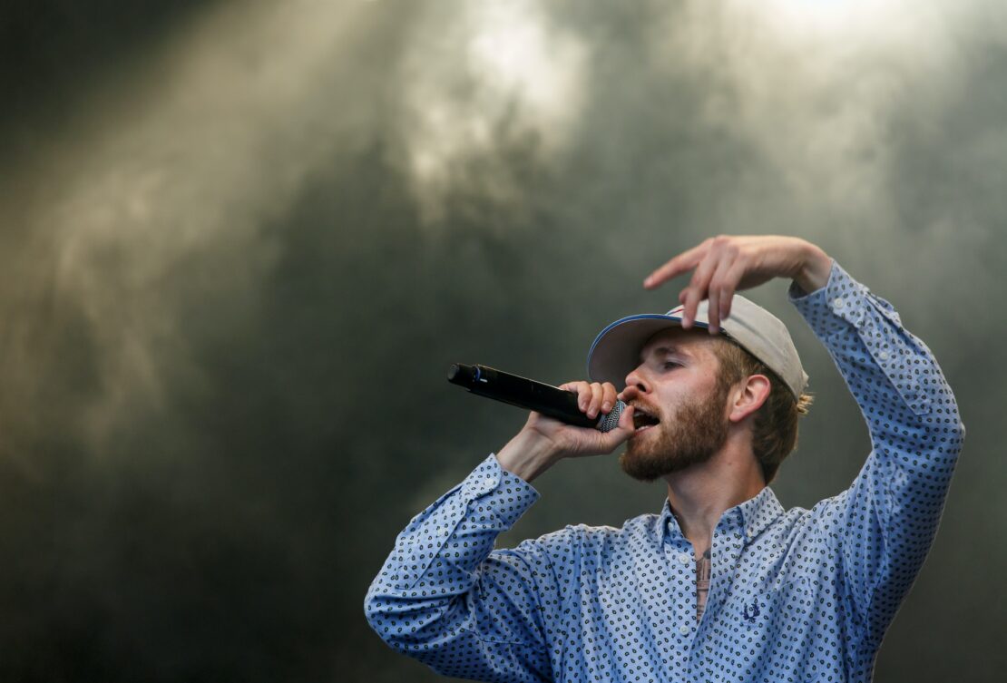 a bearded man holding a microphone and singing